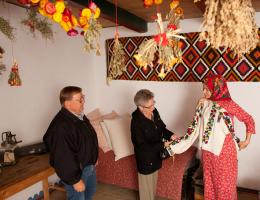A woman shows a traditional Ukrainian shirt to two visitors